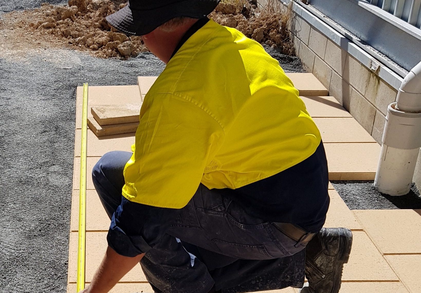 Landscaper_using_tape_measure_to_make_sure_that_the_pavers_are_laid_in_a_perfect_square_area